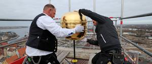 Arbeiter bei der Turmsanierung von St. Nikolai in Berlin: Eine der beiden vergoldeten Turmkugeln wird neu eingesetzt.