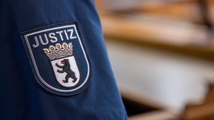 Ein Abzeichen mit dem Wort «Justiz» und dem Landeswappen von Berlin ist an der Uniform eines Justizvollzugsbeamten im Kriminalgericht Moabit angebracht.