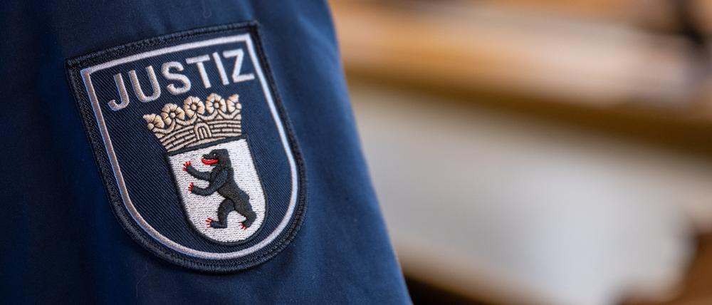 Ein Abzeichen mit dem Wort «Justiz» und dem Landeswappen von Berlin ist an der Uniform eines Justizvollzugsbeamten im Kriminalgericht Moabit angebracht.