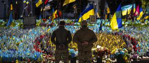 Ukrainische Soldaten stehen auf dem Unabhängigkeitsplatz im Zentrum von Kiew neben ukrainischen Flaggen und Fotos, die zum Gedenken an im Krieg gefallene Zivilisten und Soldaten aufgestellt wurden.