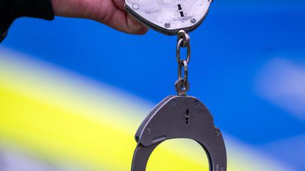 Ein Polizist hält während einer Verkehrskontrolle ein Paar Handschellen. (Symbolbild)