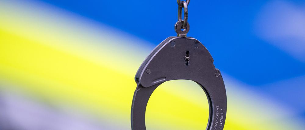 Ein Polizist hält während einer Verkehrskontrolle ein Paar Handschellen. (Symbolbild)