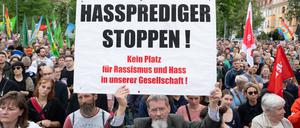 Teilnehmer einer Kundgebung stehen auf dem Pohlandplatz und halten ein Schild mit der Aufschrift ·Hassprediger stoppen·. 
