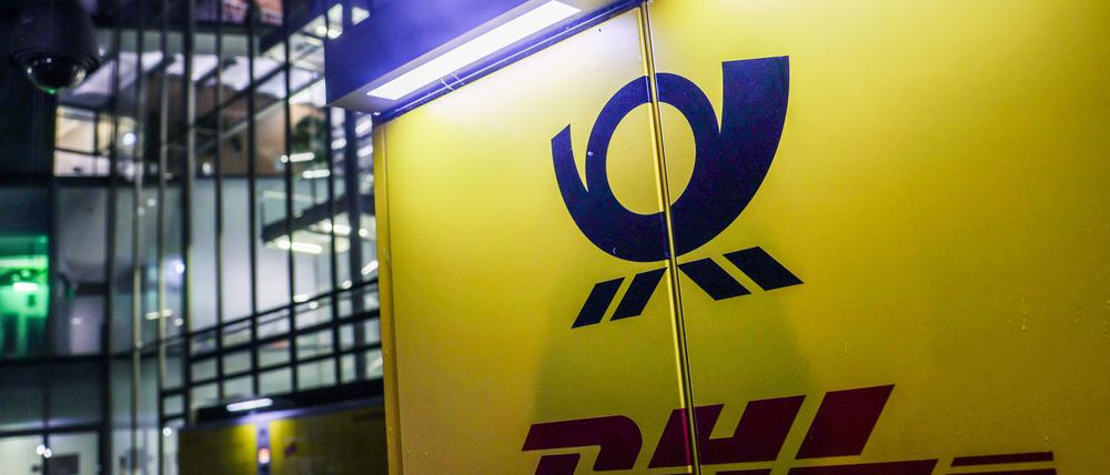 03.05.2024, Nordrhein-Westfalen, Bonn: Die Logos von Deutsche Post und DHL hängen am Posttower an einer Packstation. Die Deutsche Post AG hält ihre Hauptversammlung ab. Die Firma hat sich in DHL umbenannt, außer an der Börse, dort heißt sie weiterhin Deutsche Post AG. Foto: Oliver Berg/dpa +++ dpa-Bildfunk +++