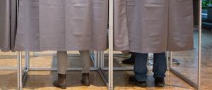 Zwei Wähler in Wahlkabinen.