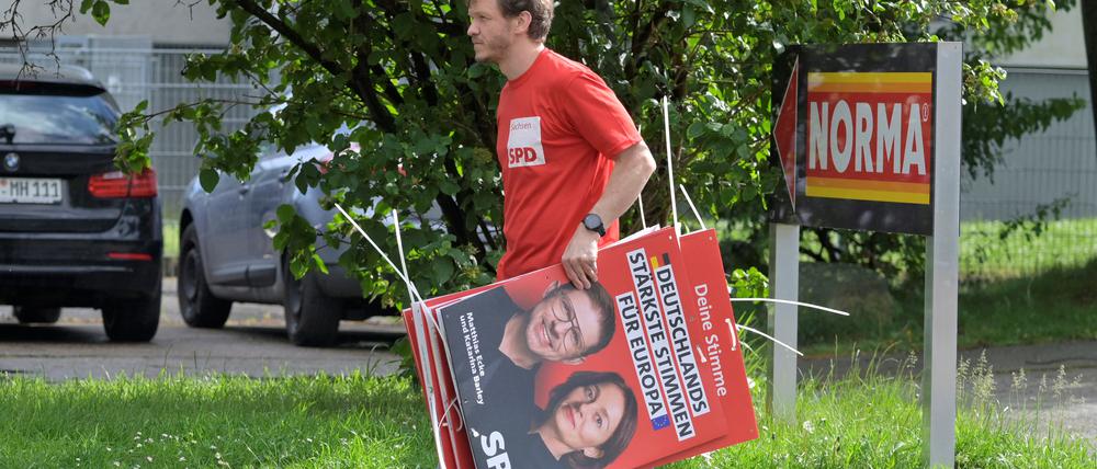 Im Einsatz für die Gesellschaft. Ein Freiwilliger hängt Wahlplakate auf.