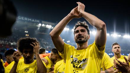 Mats Hummels steht im Stadion inmitten seiner Teamkollegen und klatscht über Kopf in die Hände.