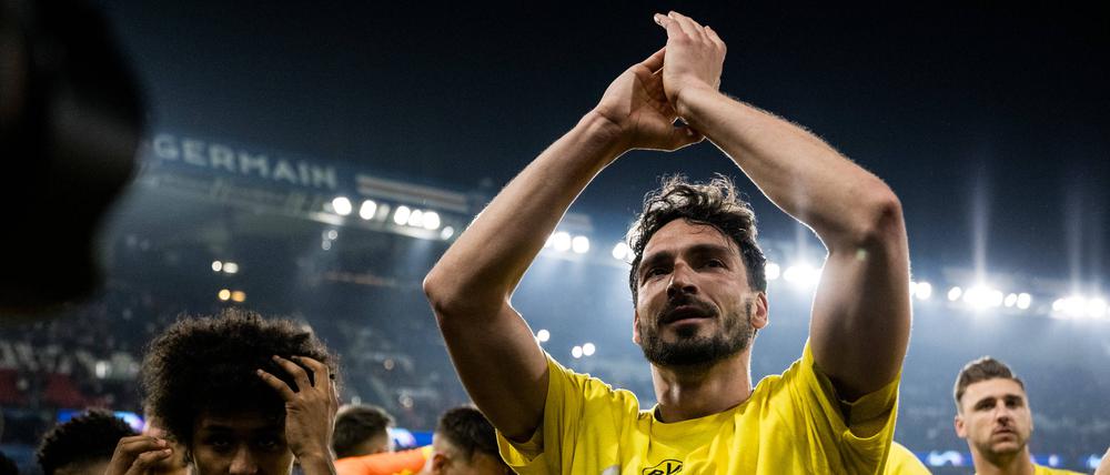 Mats Hummels steht im Stadion inmitten seiner Teamkollegen und klatscht über Kopf in die Hände.