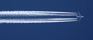 Ein Flugzeug hinterlässt am wolkenlosen Himmel Kondensstreifen.