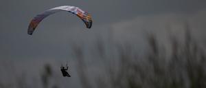 ARCHIV - 21.06.2023, Hessen, Gersfeld: Ein Gleitschirmflieger wird von der Sonne angeschienen während er in einer Wiese landet. 