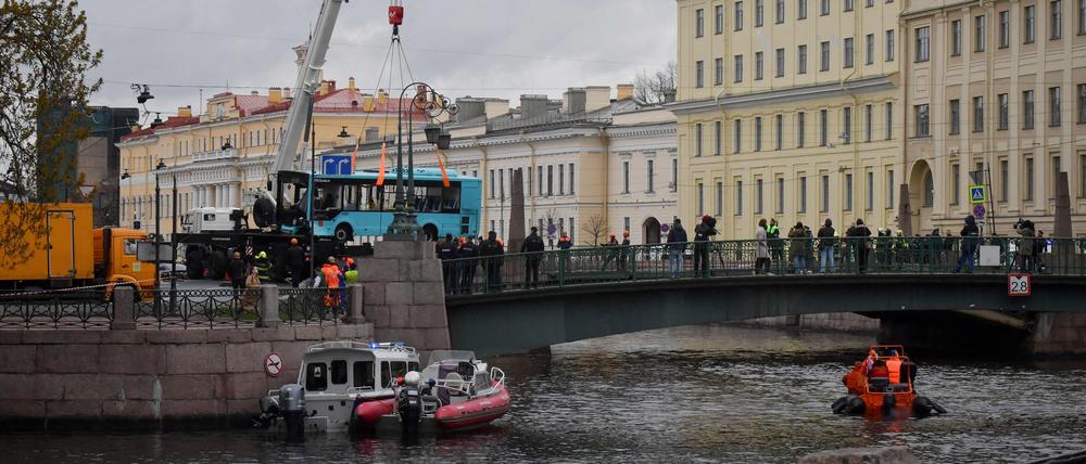 Rettungskräfte heben den Bus mit einem Kran aus dem Wasser.
