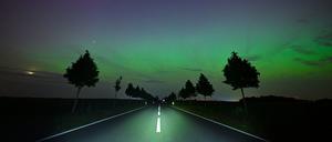 Hellgrün und ein wenig rötlich leuchten Polarlichter am Nachthimmel im Landkreis Märkisch-Oderland in Ostbrandenburg. Die Nordlichter (Aurora borealis) werden durch eine Wolke elektrisch geladener Teilchen eines Sonnensturms in der Erdatmosphäre erzeugt.