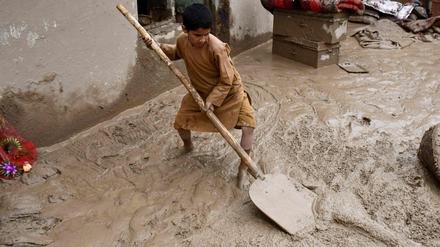 Ein afghanischer Junge schaufelt Schlamm aus dem Hof eines Hauses, nachdem es in einem Dorf im Bezirk Baghlan-e-Markazi in der Provinz Baghlan am 11. Mai 2024 zu heftigen Überschwemmungen gekommen war.