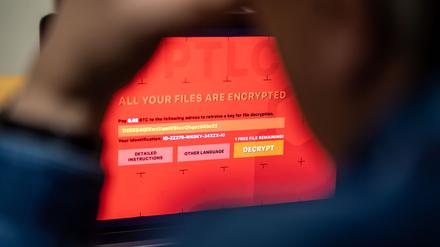 Ein Mann sitzt vor einem Laptop, der mit einem fiktiven Verschlüsselungstrojaner (Ransomware) befallen ist.