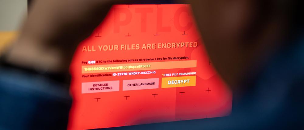 Ein Mann sitzt vor einem Laptop, der mit einem fiktiven Verschlüsselungstrojaner (Ransomware) befallen ist.