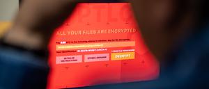 Ein Mann sitzt vor einem Laptop, der mit einem fiktiven Verschlüsselungstrojaner (Ransomware) befallen ist.