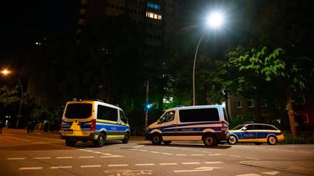 Einsatzfahrzeuge der Polizei stehen vor einem Hochhaus im Hamburger Bezirk Altona, nachdem eine Person mit einer Schusswaffe einen Großeinsatz ausgelöst hat.