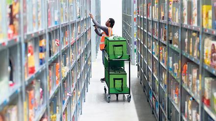 Ein Mitarbeiter eines Lebensmittellieferdienstes packt im Depot der Firma in Berlin die bestellten Waren in eine Transporttasche.