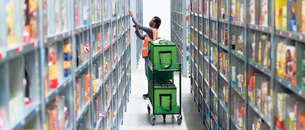 Ein Mitarbeiter eines Lebensmittellieferdienstes packt im Depot der Firma in Berlin die bestellten Waren in eine Transporttasche.