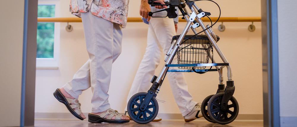 Eine Pflegekraft geht in einem Pflegeheim mit einer älteren Dame über einen Korridor (Symbolbild).
