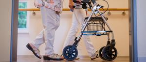 Eine Pflegekraft geht in einem Pflegeheim mit einer älteren Dame über einen Korridor (Symbolbild).