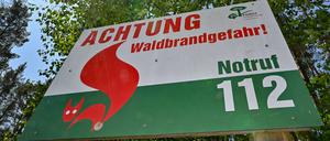 ARCHIV - 26.05.2023, Brandenburg, Briesen: Ein Schild vom Landesbetrieb Forst Brandenburg mit der Aufschrift «Achtung Waldbrandgefahr! Notruf 112» steht vor Bäumen. (zu dpa: «Hohe Waldbrandgefahr zum Wochenstart in Brandenburg») Foto: Patrick Pleul/dpa +++ dpa-Bildfunk +++