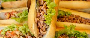 Ein Mitarbeiter greift mit einer Zange ein Brötchen mit Nordseekrabben am Tresen eines Fischbrötchen-Imbisses an den Landungsbrücken in Hamburg.