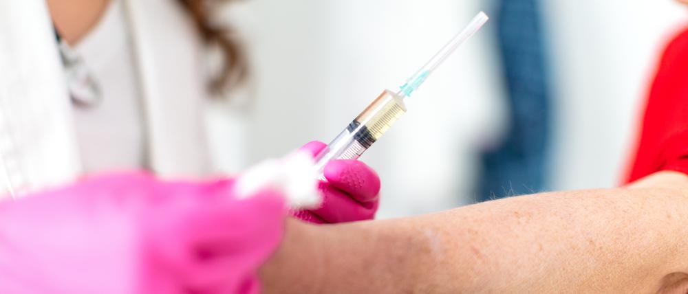 Eine Ärztin ist kurz davor, einem Patienten eine Spritze zu verabreichen.