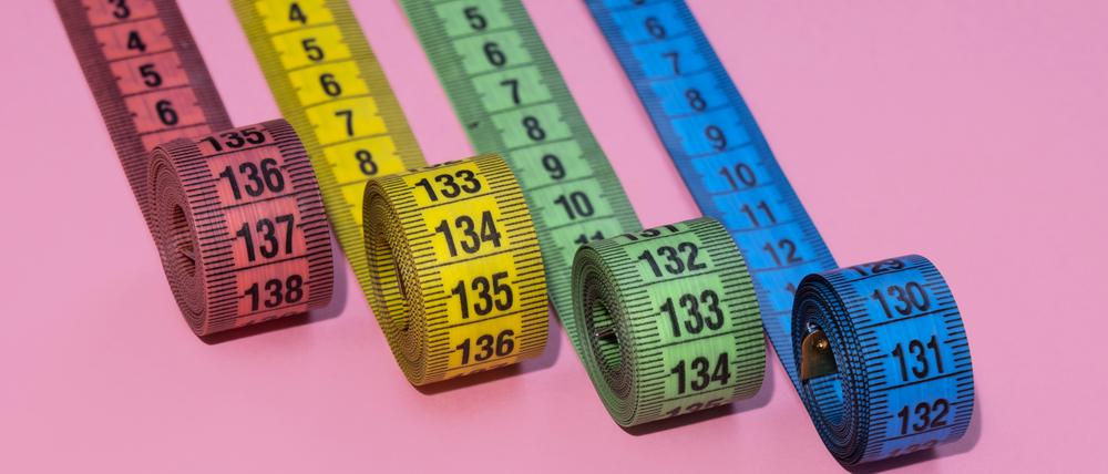 Vier bunte Maßbänder vor einem pinken Hintergrund. Wer mit Ozempic, Wegovy und Co. behandelt wird, nimmt ab. Nur, für wie lange?