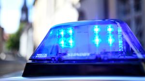 Ein Polizeiauto mit blinkendem Blaulicht steht vor einem Gebäude. 