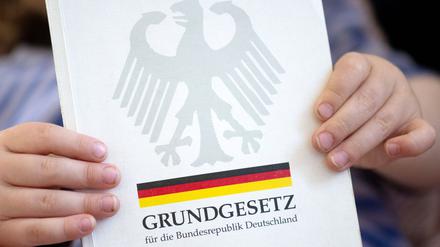 Ein kleiner Junge hält eine Ausgabe des Grundgesetzes in seinen Händen. 