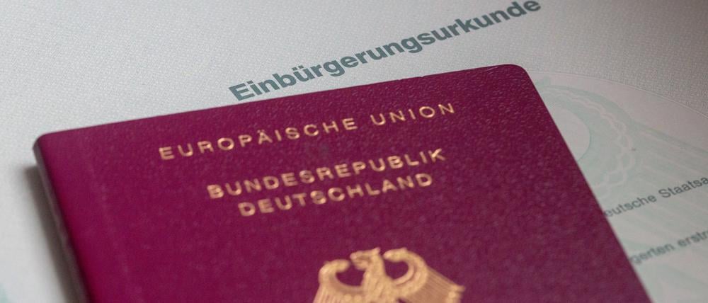 Eine Einbürgerungsurkunde der Bundesrepublik Deutschland und ein deutscher Reisepass liegen auf einem Tisch (Symbolbild).