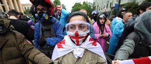 Eine Frau hat sich beim Protest gegen das sogenannte Agentengesetz in Tiflis in die georgische Flagge gehüllt.