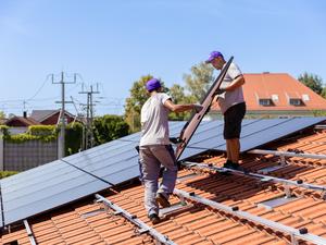 Installateure montieren eine Solaranlage auf einem Hausdach.