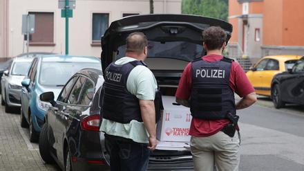 Nach einer Wohnungsdurchsuchung verladen Polizisten einen Karton mit sichergestellten Gegenständen in einen Wagen.