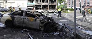 Ein ausgebranntes Auto steht vor einem Wohnhaus, in dem ein Brand wütete.