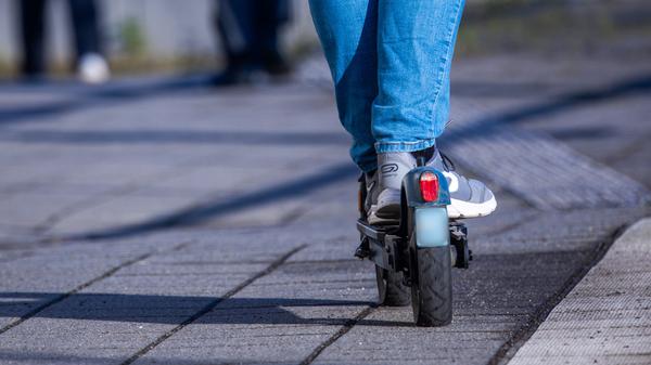 Ein Mensch fährt mit seinem E-Scooter über den Bahnsteig.