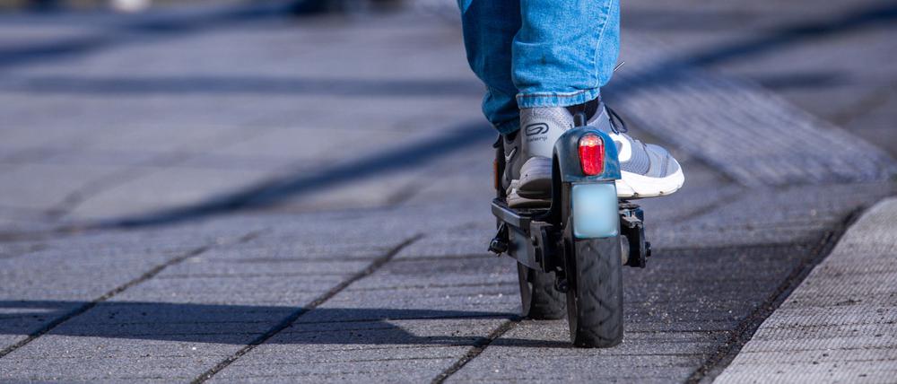 Ein Reisender fährt mit seinem E-Scooter über den Bahnsteig.