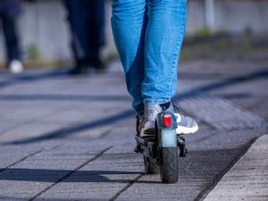 Ein Mensch fährt mit seinem E-Scooter über den Bahnsteig.
