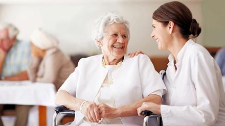Eine Seniorin unterhält sich mit einer Pflegekraft.