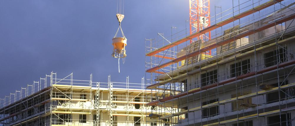 Rohbauten für Wohnhäuser in Leipzig werden in der Dämmerung beleuchtet.
