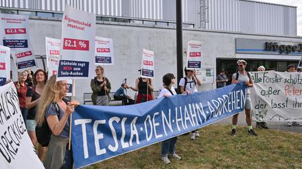 16.05.2024, Brandenburg, Grünheide: Teilnehmer der Bündnisinitiative «Tesla den Hahn abdrehen» protestieren vor der Müggelspreehalle in Hangelsberg, einem Ortsteil von Grünheide, wo am späten Nachmittag die Gemeindevertreter über die Erweiterungspläne der Tesla-Fabrik in Grünheide abstimmen wollen. Foto: Patrick Pleul/dpa +++ dpa-Bildfunk +++