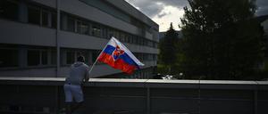 Slowakei, Banska Bystrica: Ein Mann schwenkt die slowakische Nationalflagge vor dem F. D. Roosevelt Universitätskrankenhaus, in dem der angeschossene und verwundete slowakische Premierminister Fico behandelt wird.