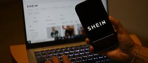 Das Shein-Logo ist auf einem Smartphone zu sehen, während die Webseite des chinesischen Online-Händlers auf einem Laptop geöffnet ist.
