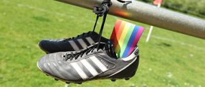 Eine Regenbogenbinde steckt in einem Fußballschuh.   