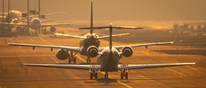 Flugzeuge rollen auf dem Flughafen Frankfurt im letzten Sonnenlicht des Tages über die Rollbahn.