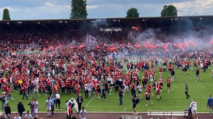 Zahlreiche  Fans feiern ausgelassen den Aufstieg ihrer Mannschaft auf dem Spielfeld.