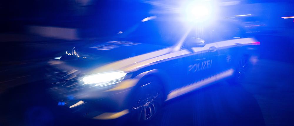 Ein Polizeifahrzeug fährt mit Blaulicht an einem Gebäude vorbei. (Symbolbild)
