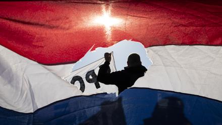 Riss in der Flagge. Teilnehmer einer Demonstration gegen die Corona-Maßnahmen in Amsterdam.
