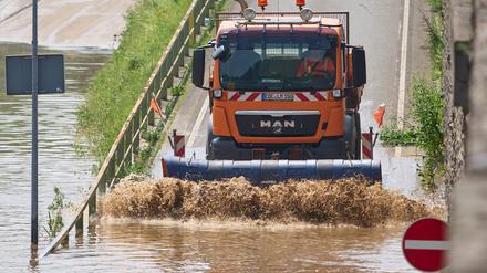 Ein Schneepflug schiebt Hochwasserschlamm von einer Straße in Kobern-Gondorf in Rheinland-Pfalz.